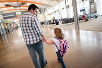 Father and daughter walking through airport