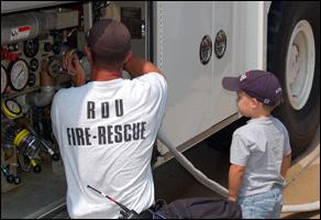 Fire Engineer David Robbins shows one of RDU’s young visitors how to attach a hose to a fire truck.